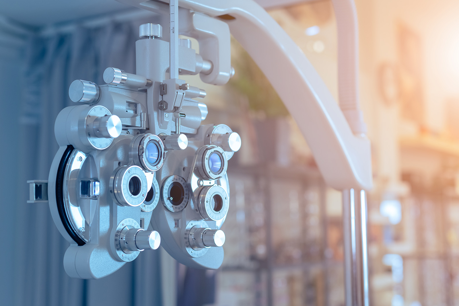 The image shows an optical examination chair with an attached eye exam device, placed indoors under bright lighting.