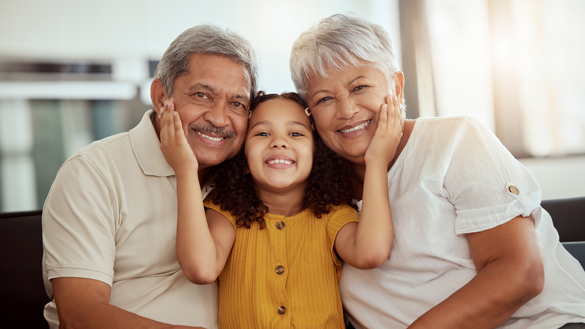 The image depicts an elderly couple and a young child posing together for a photo, with both adults smiling at the camera.