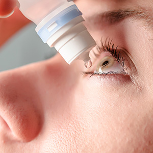 The image depicts a close-up view of a person s eye with an eyedropper held over it, ready for use.