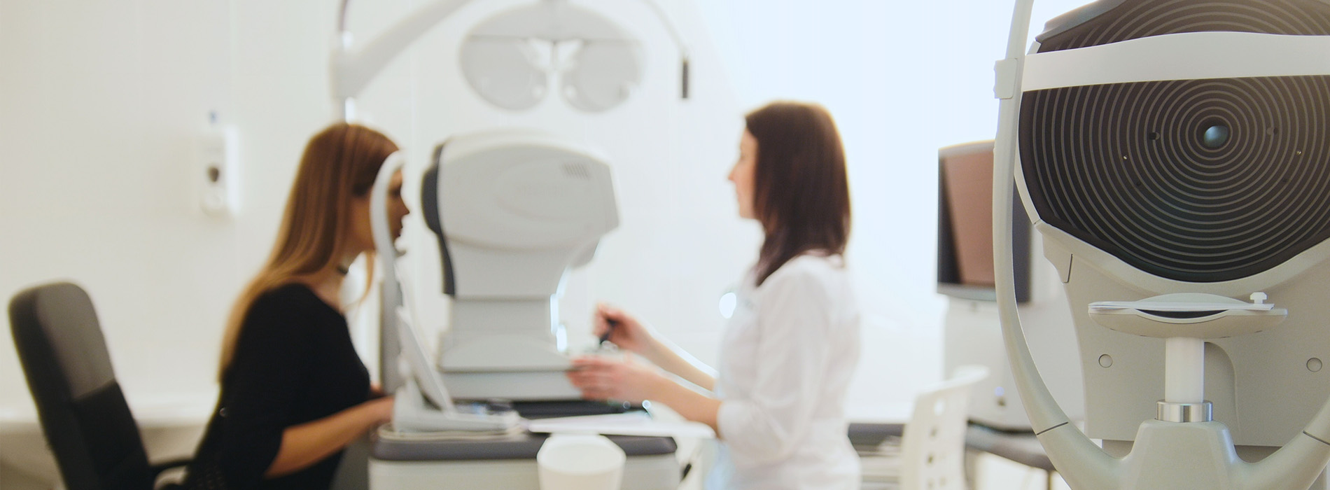 Two individuals engaged in an eye examination, with specialized equipment visible in the background.