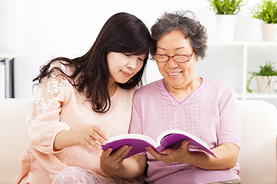 Two people seated on a couch, engaged in reading a book together.